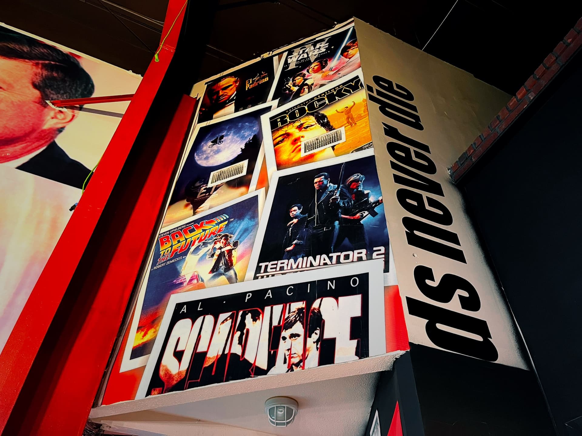 A wall of framed action movie posters inside the gym under the words legends never die
